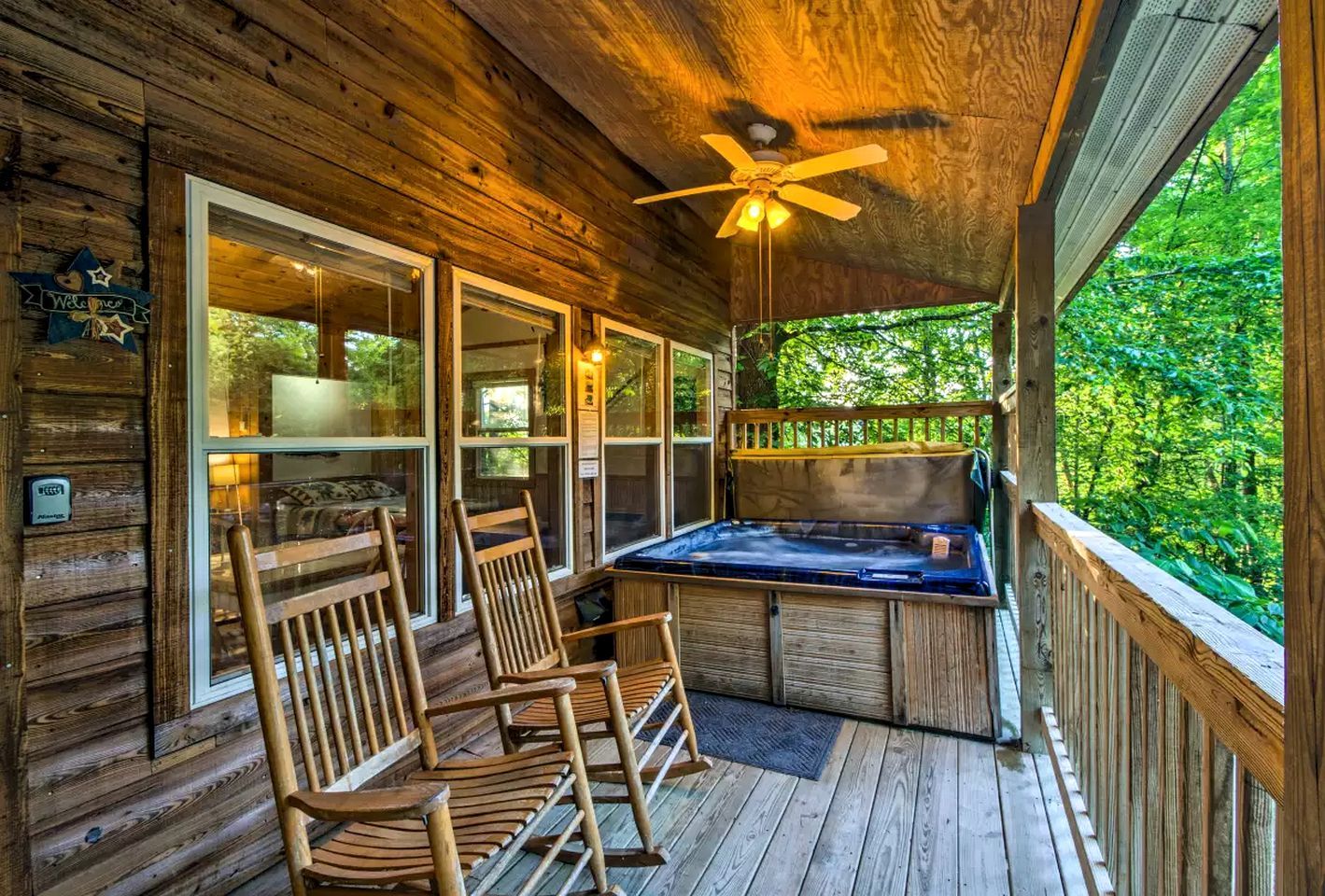 A wooden cabin with a deck, a hot tub, and two rocking chairs.