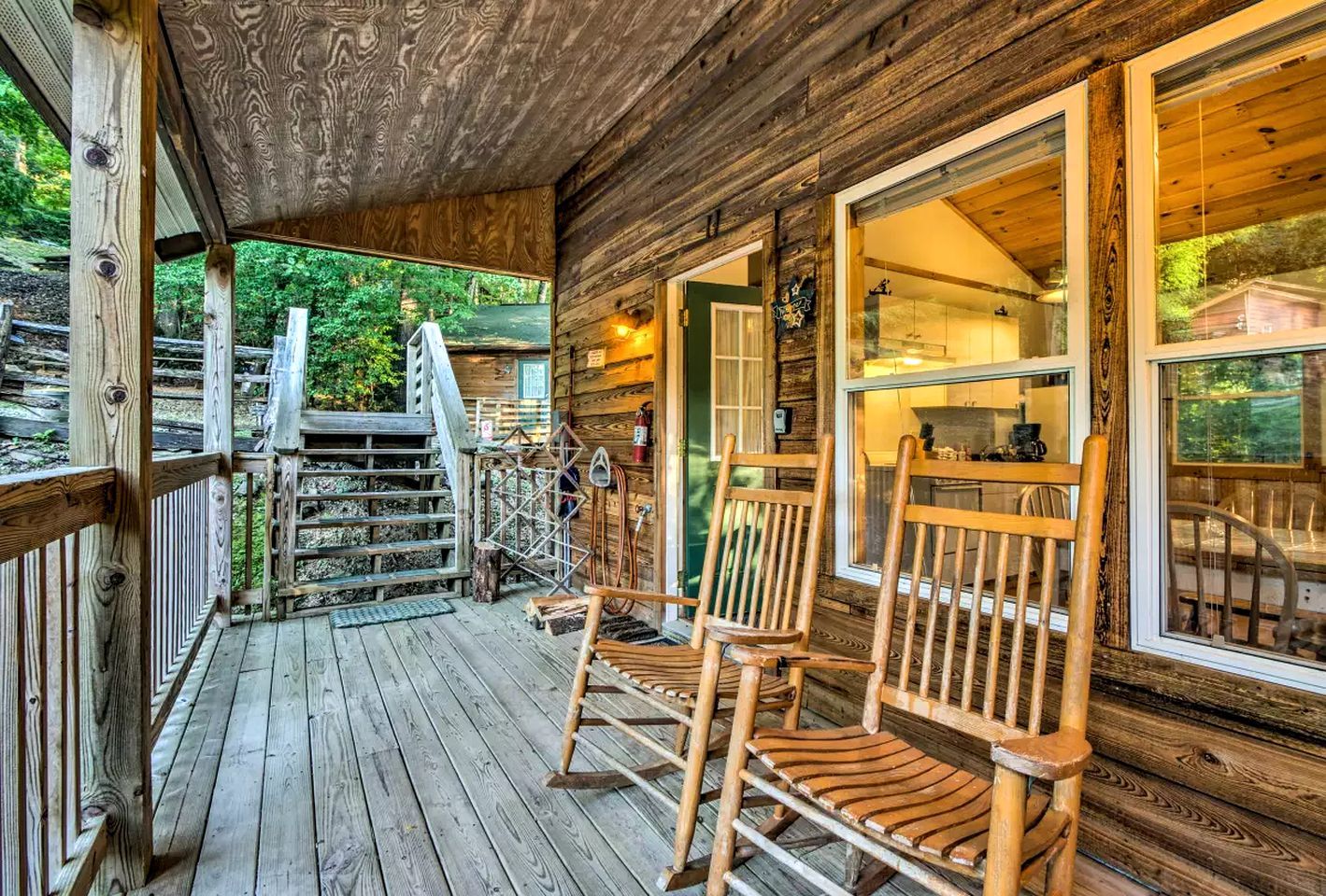 A wooden cabin with a porch, wooden chairs, and a staircase leading to the entrance.