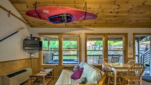 A cabin interior with a bed, a table, chairs, a heater, and large windows. - Tree-House Style Cabin with Forest Views, Nantahala National Fores, North Carolina (Bryson City)