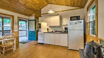A wooden interior with a kitchen, dining area, and a view through a door.