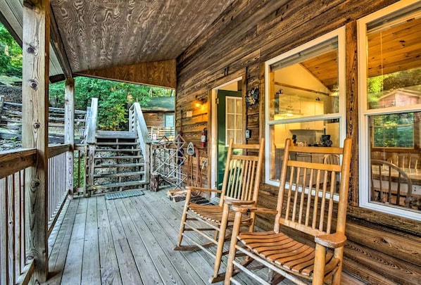 A wooden cabin with a porch, wooden chairs, and a staircase leading to the entrance.