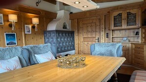 A wooden dining table with a decorative centerpiece, surrounded by upholstered chairs with fur throw pillows. - Cozy holiday home with mountain views (Breitenbach am Inn)