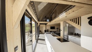 Una cocina moderna con una isla grande, un horno empotrado y un amplio ventanal con vistas a un espacio exterior pintoresco.
