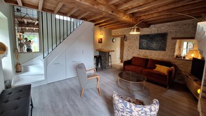 Een ruime woonkamer met een houten plafond, een trap, een rode bank en een glazen salontafel.