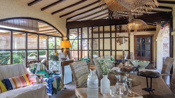 A room with a wooden ceiling, large windows, wicker furniture, and a table with glassware. - Podere La Botte, Pool, Lari (Lari)