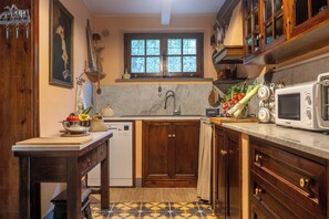 A compact kitchen with wooden cabinets, a built-in sink, a microwave, and a window above the sink. - Podere La Botte, Pool, Lari (Lari)