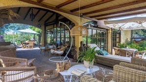 An outdoor seating area with wicker furniture, a hanging lamp, and a view of greenery. - Podere La Botte, Pool, Lari (Lari)
