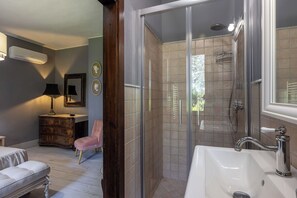 Een badkamer met een douche met glazen wanden, een witte wastafel en een badkamermeubel.