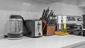 Una encimera de cocina con cafetera, tostadora, bloque de cuchillos y pulverizador.