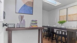 Una cocina moderna con una isla central, taburetes de bar y un reloj en la pared.