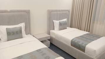 Een hotelkamer met twee bedden, elk met een kussen en een nachtkastje.