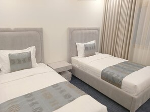 A hotel room with two beds, each with a pillow and a bedside table. - Velmist Residence Abha (Abha)