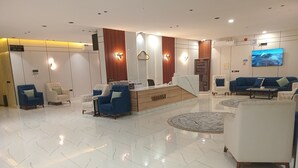 A modern lobby with a reception desk, seating area, and a large screen. - Velmist Residence Abha (Abha)