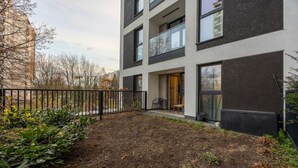 Un edificio moderno con techo plano, ventanas amplias y patio empedrado.