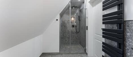 A modern bathroom with a shower, a towel rack, and a marble floor.