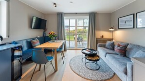 Ein modernes Wohnzimmer mit einer Couch, einem Esstisch und einem Fernseher.