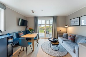 Ein modernes Wohnzimmer mit einer Couch, einem Esstisch und einem Fernseher.