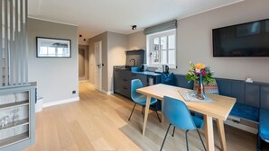 Eine moderne Küche mit Essbereich, einem an der Wand montierten Fernseher und einer Treppe, die zu einer weiteren Ebene führt.