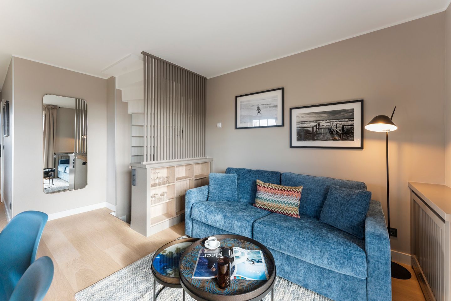 A modern living room with a blue sofa, a coffee table, and a mirror.