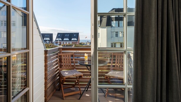 Ein Balkon mit Holzgeländern, zwei Stühlen und einem Tisch.