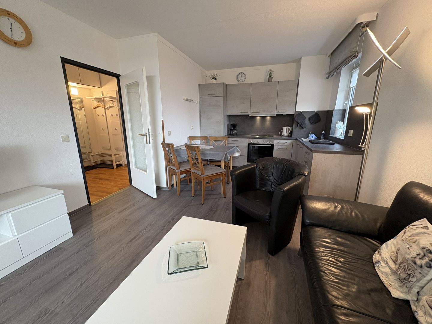 Un espacio habitable compacto con kitchenette, comedor y zona de estar.