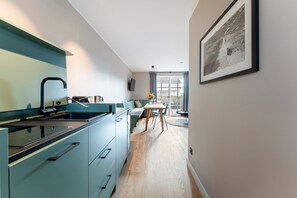 Une cuisine moderne dotée d’une cuisinière intégrée, d’un coin repas avec une table et des chaises, et d’une grande fenêtre agrémentée de rideaux.