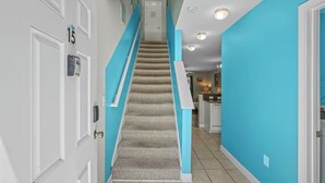 A staircase with a carpeted finish, white doors, and a blue accent wall. - Quiet 2BR Townhome Near Beach, Boardwalk & Hospitals (Myrtle Beach)