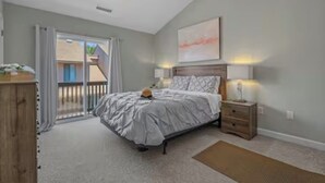 A bedroom with a bed, a nightstand, a dresser, and a sliding glass door leading to a balcony. - Quiet 2BR Townhome Near Beach, Boardwalk & Hospitals (Myrtle Beach)