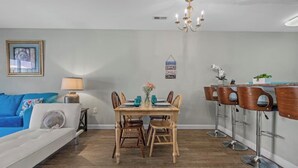 A dining area with a wooden table, four chairs, and a chandelier. - Quiet 2BR Townhome Near Beach, Boardwalk & Hospitals (Myrtle Beach)