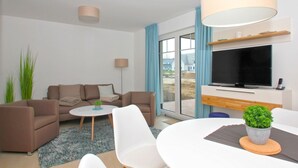A modern living room with a sofa, coffee table, and TV. - Beachfront apartment with terrace, use of swimming pool and sauna - Rex Rugia H-1010 - (Mönchgut)