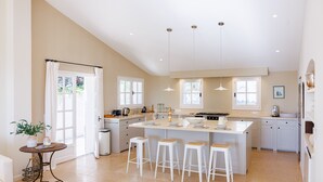 A modern kitchen with a central island, white cabinetry, and pendant lighting. - Mas Bellevue – Heated Pool & Exceptional Sea View (Saint Paul de Vence)