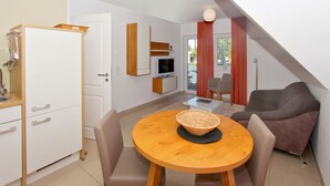 Un espacio habitable compacto con kitchenette, una zona de comedor con mesa redonda y un área de estar con sofá.