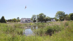 Ein großes Gebäude mit zahlreichen Fenstern und einem Teich im Vordergrund.
