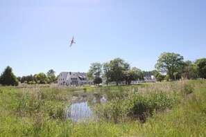 Ein großes Gebäude mit zahlreichen Fenstern und einem Teich im Vordergrund.