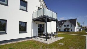 A modern two-story house with a balcony, a patio with outdoor furniture, and a well-maintained lawn. - Beachfront apartment with terrace, use of swimming pool and sauna - Rex Rugia H-1010 - (Mönchgut)