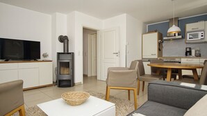 Un salon moderne avec un téléviseur, un canapé et une cheminée. Il y a également un coin repas avec une table et des chaises.