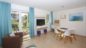 Una sala de estar moderna con televisor, mesa de comedor, sillas y sofá.