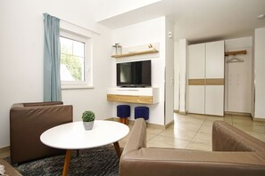 Ein modernes Wohnzimmer mit einer Couch, einem runden Tisch, einem Fernseher und einem Kleiderschrank.