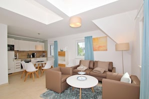 A modern living room with a sofa set, a coffee table, and a dining area with chairs and a table. - Beachfront apartment with balcony, use of swimming pool and sauna - Rex Rugia H-1010 - (Mönchgut)