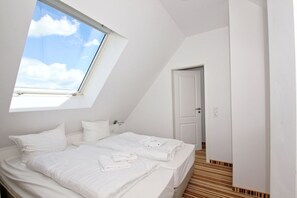 Ein Schlafzimmer mit Dachfenster, einem Bett mit weißer Bettwäsche und Holzboden.