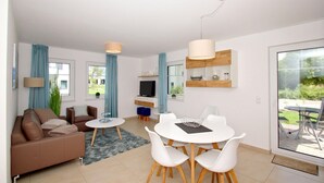 Un salon moderne comprenant un canapé, un téléviseur, une table à manger et des chaises.