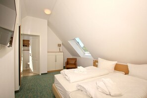 A hotel room with a bed, a desk, a chair, a wardrobe, and a skylight. - Beachfront apartment with balcony, use of swimming pool and sauna - Rex Rugia H-1010 - (Mönchgut)