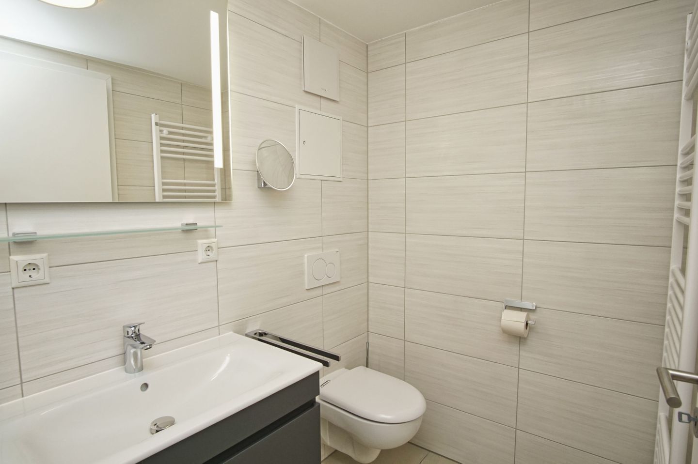 Une salle de bain moderne avec un lavabo blanc, un miroir et des toilettes.