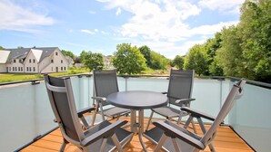 A balcony with a table and chairs, overlooking a residential area with houses and trees. - Beachfront apartment with balcony, use of swimming pool and sauna - Rex Rugia H-1010 - (Mönchgut)