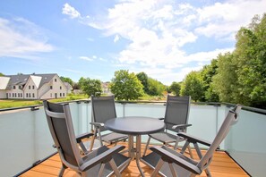 A balcony with a table and chairs, overlooking a residential area with houses and trees. - Beachfront apartment with balcony, use of swimming pool and sauna - Rex Rugia H-1010 - (Mönchgut)