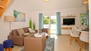 A modern living room with a sofa set, a coffee table, a TV, and a dining area with chairs. - Beachfront apartment with balcony, use of swimming pool and sauna - Rex Rugia H-1010 - (Mönchgut)