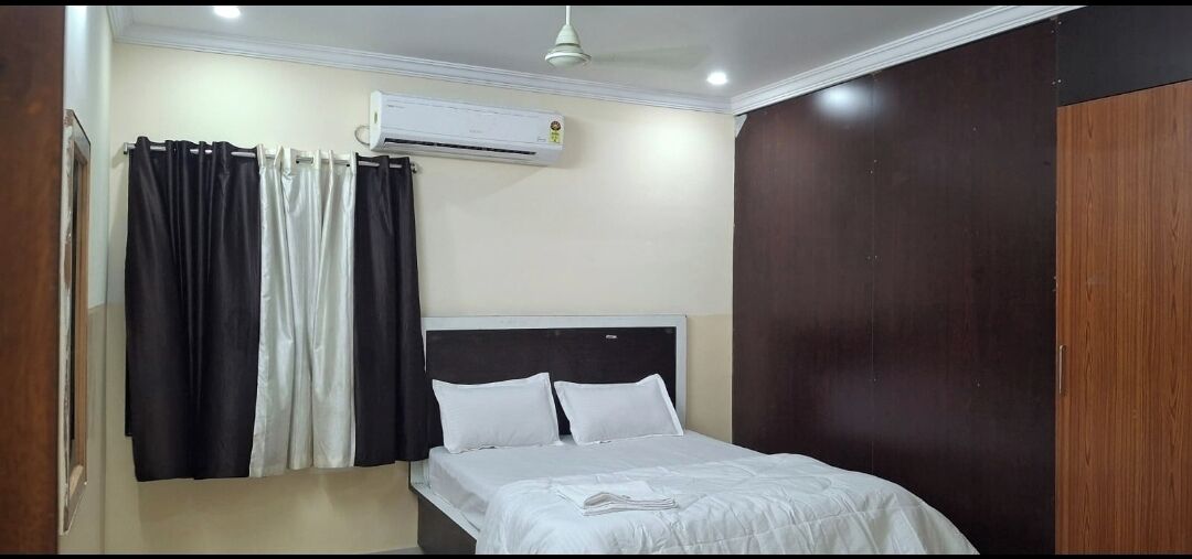 Un dormitorio con cama, cortinas blancas, ventilador de techo y aire acondicionado.