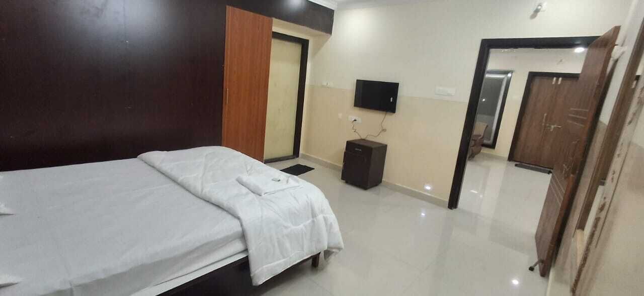 Une chambre d’hôtel avec un lit, une télévision, une petite armoire et une porte donnant sur une autre pièce.