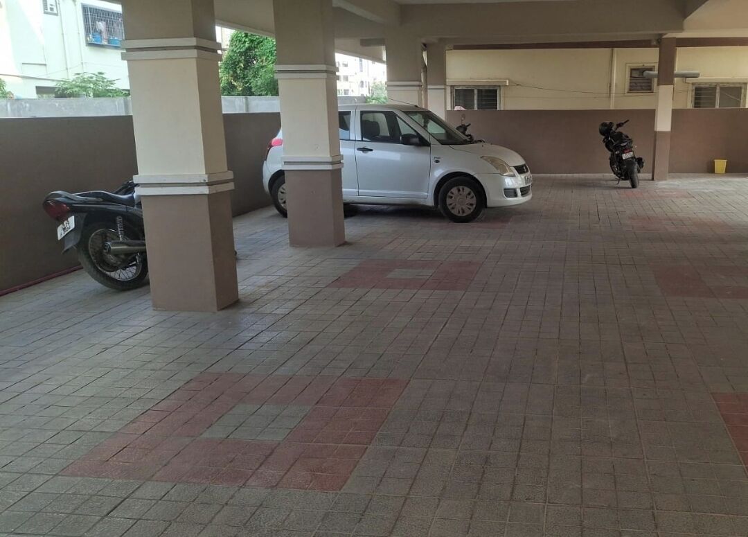A covered parking area with a white car and a motorcycle parked.