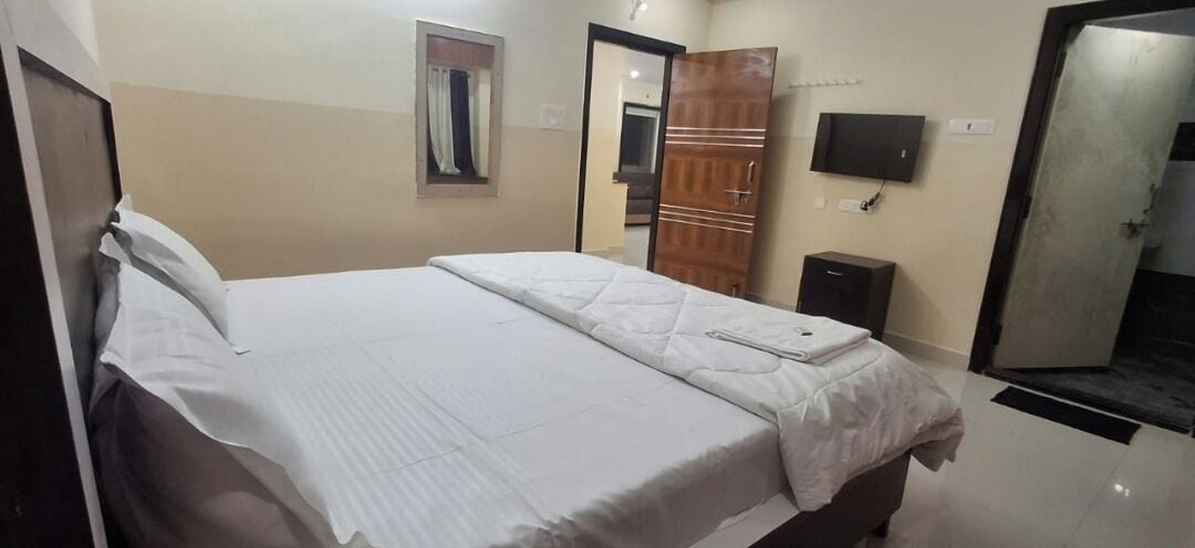 A hotel room with a bed, a wardrobe, a television, and a mirror.